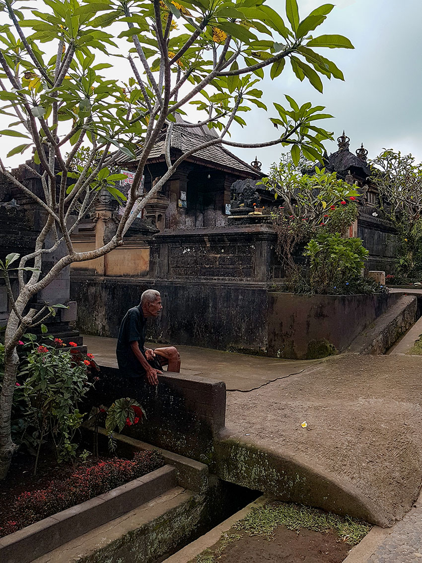Il villaggio di penglipuran a Bali.. Un anziano siede su un muretto.